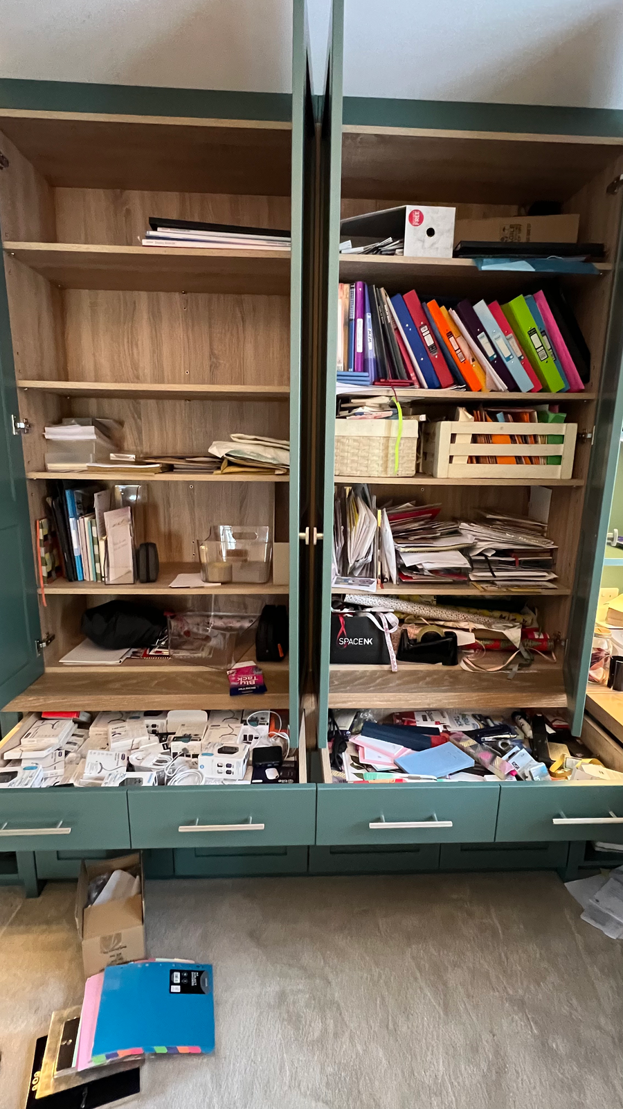 Messy office cupboards filled with paperwork, folders, and office supplies before organising.Professional organiser Hertfordshire, home office decluttering, and paperwork organisation.